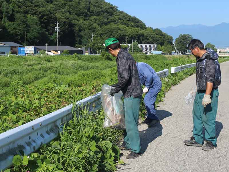 九州興業の従業員がすすき川堤防でゴミ拾いをしている